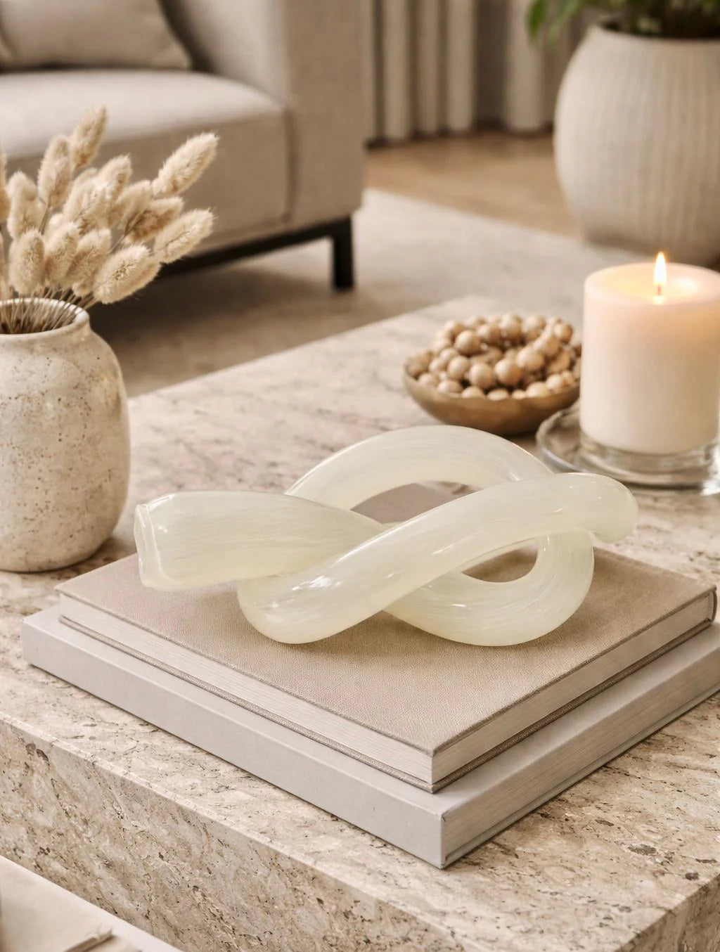 פסל קשר Ivory Loop בצבע שמנת עם ברק עדין על שולחן קפה בעיצוב מודרני