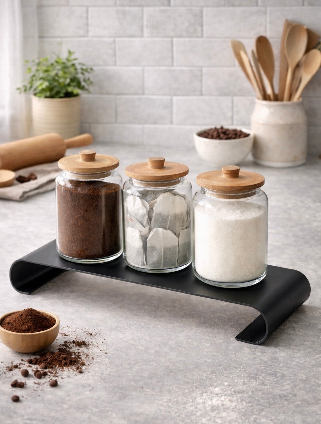 שלוש צנצנות זכוכית למטבח עם מכסי עץ על מעמד מתכת שחור - כלי אחסון מעוצבים לקפה, סוכר וקפסולות קפה בעיצוב מודרני למטבח.
