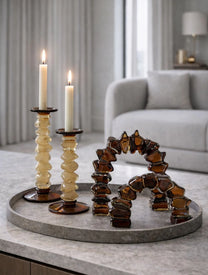 פמוטים ענבריים מדורגים Amber מזכוכית עם בסיס כהה על שולחן מעוצב