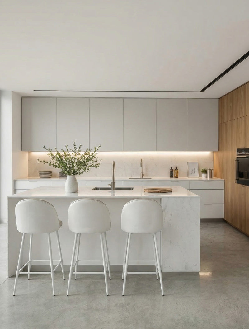 כיסא בר מרופד בד בהיר עם גב מעוגל ובסיס מתכת לבן, מסודר סביב אי במטבח מודרני בהיר