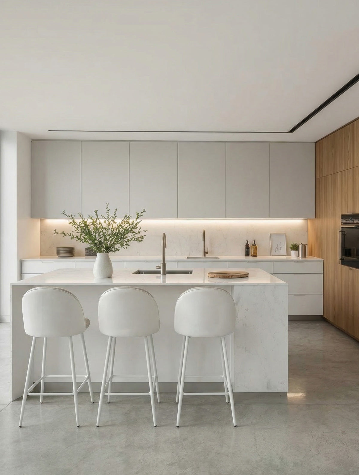 כיסא בר מרופד בד בהיר עם גב מעוגל ובסיס מתכת לבן, מסודר סביב אי במטבח מודרני בהיר