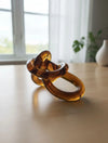 פסל קשר מזכוכית ענברית שקופה Amber Knot על שולחן בעיצוב מודרני