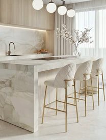 כיסא בר מרופד לבן עם נגיעות חומות על  בסיס מתכת זהב בעיצוב מודרני מינימליסטי במטבח מודרני